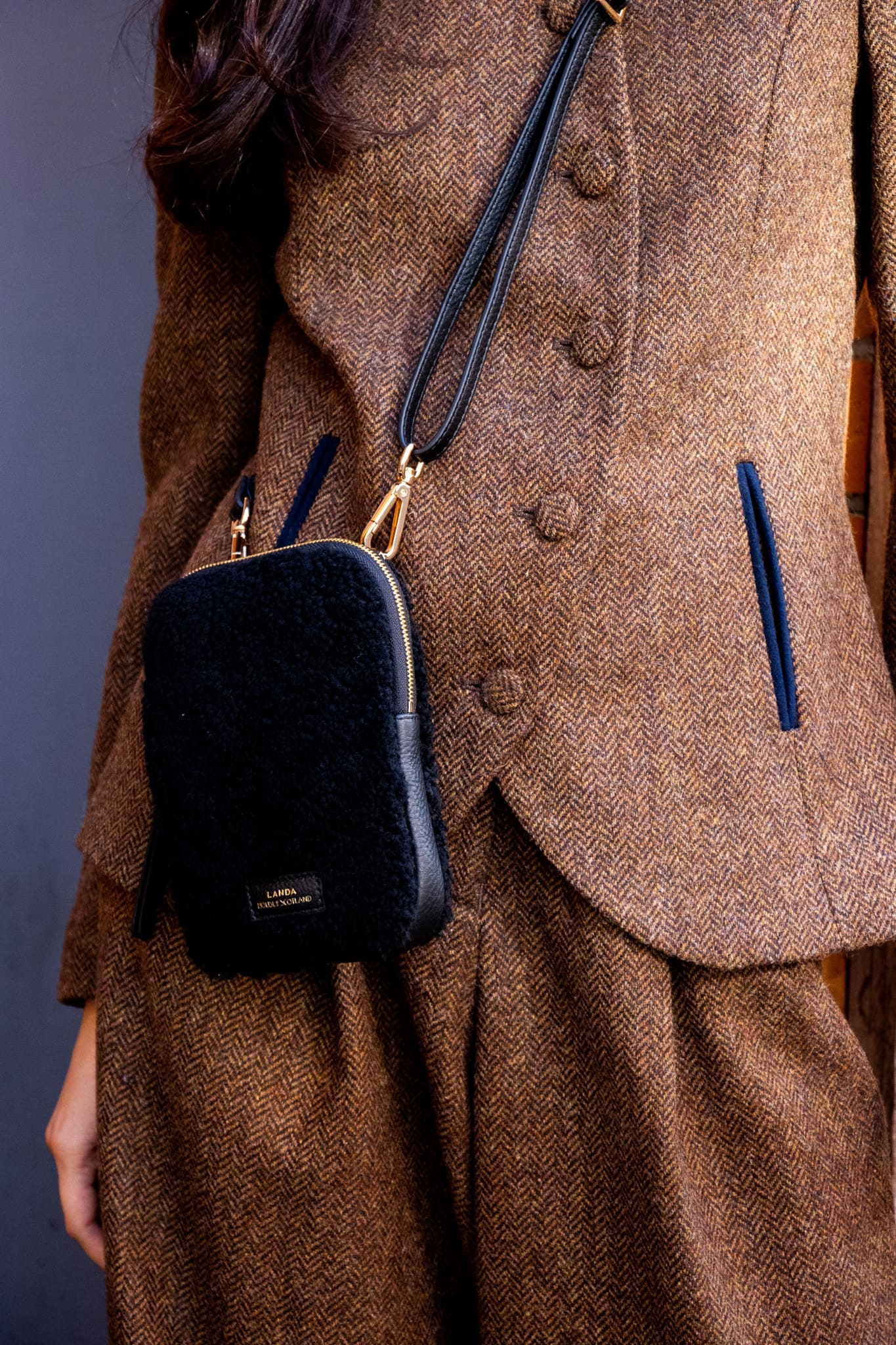 Person wearing a brown suit with a black crossbody bag