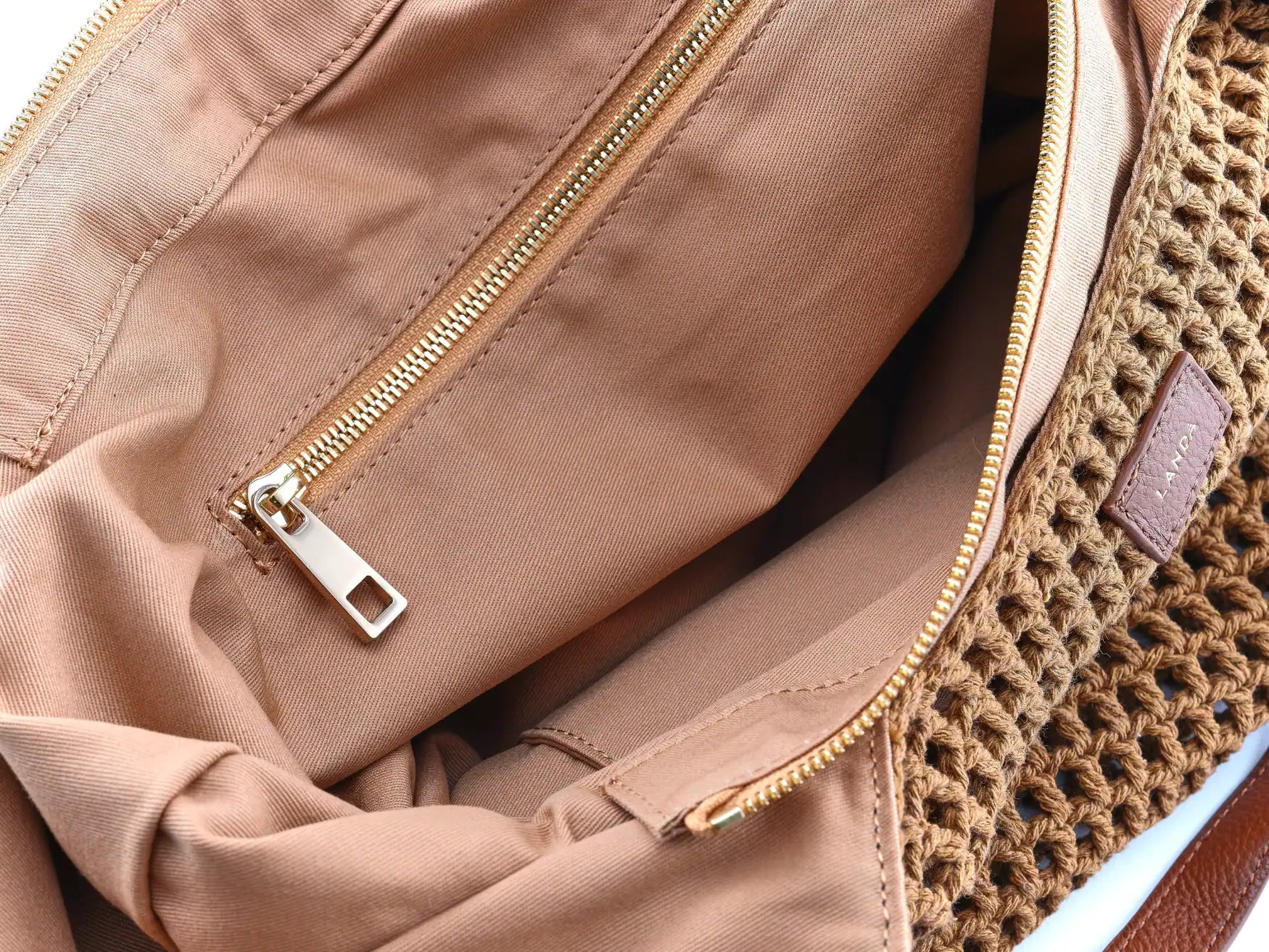 Closeup of an internal zipper pocket in a brown cotton woven handbag.