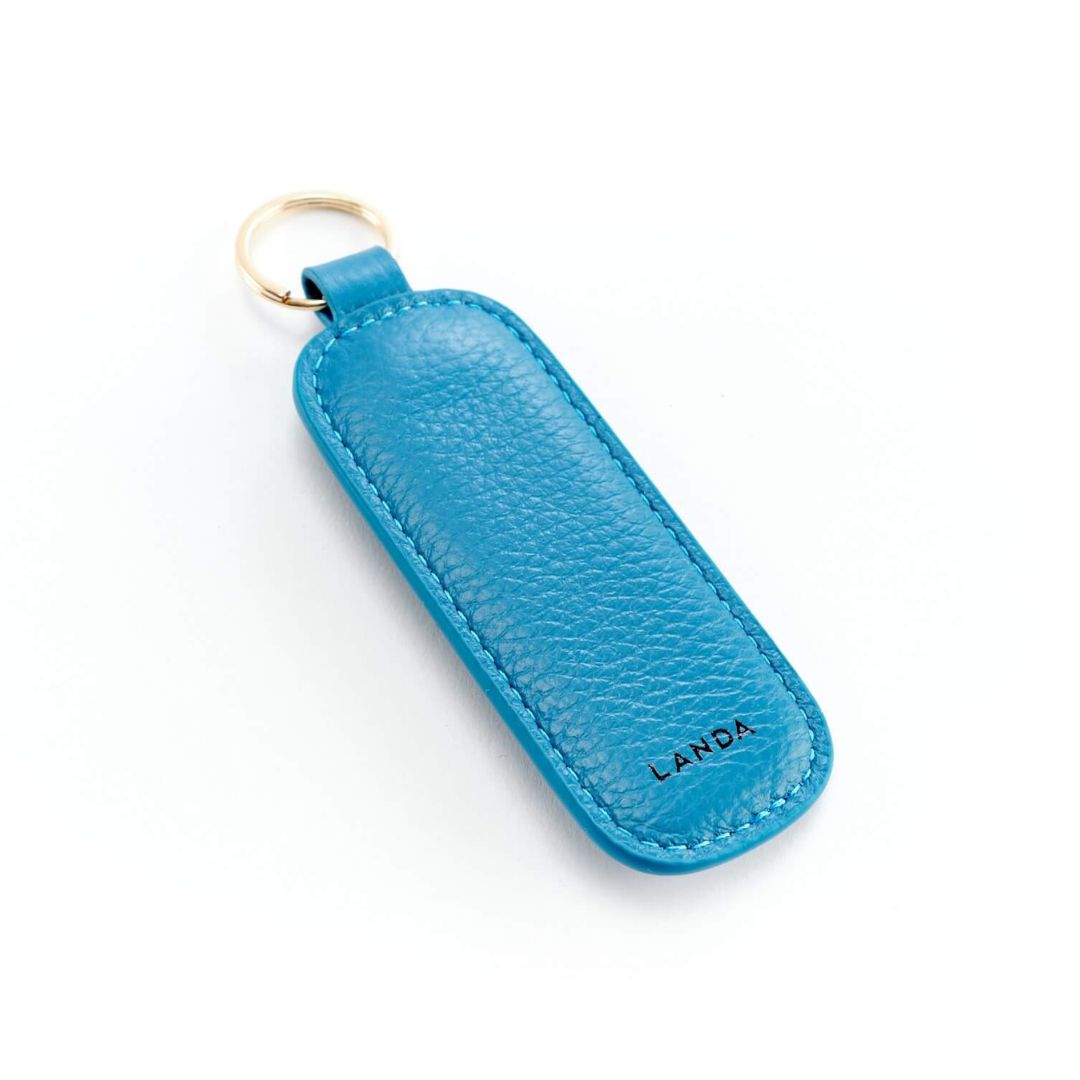 Blue leather keyring fob on a gold-coloured ring against a white background