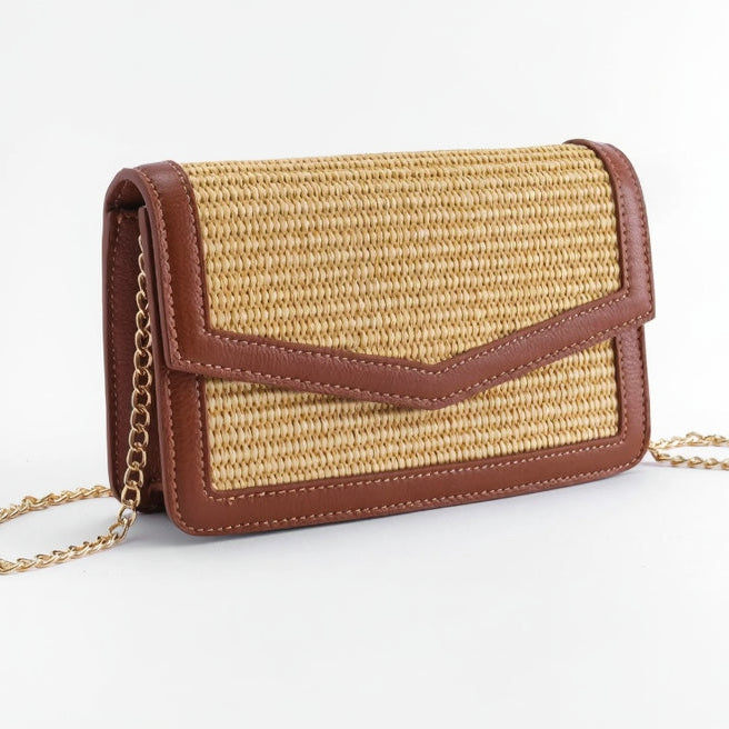 Raffia handbag with tan leather accents on a white background