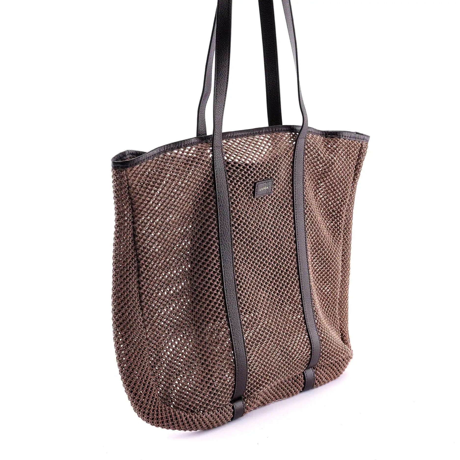 Woven beach bag with brown leather straps on a white background