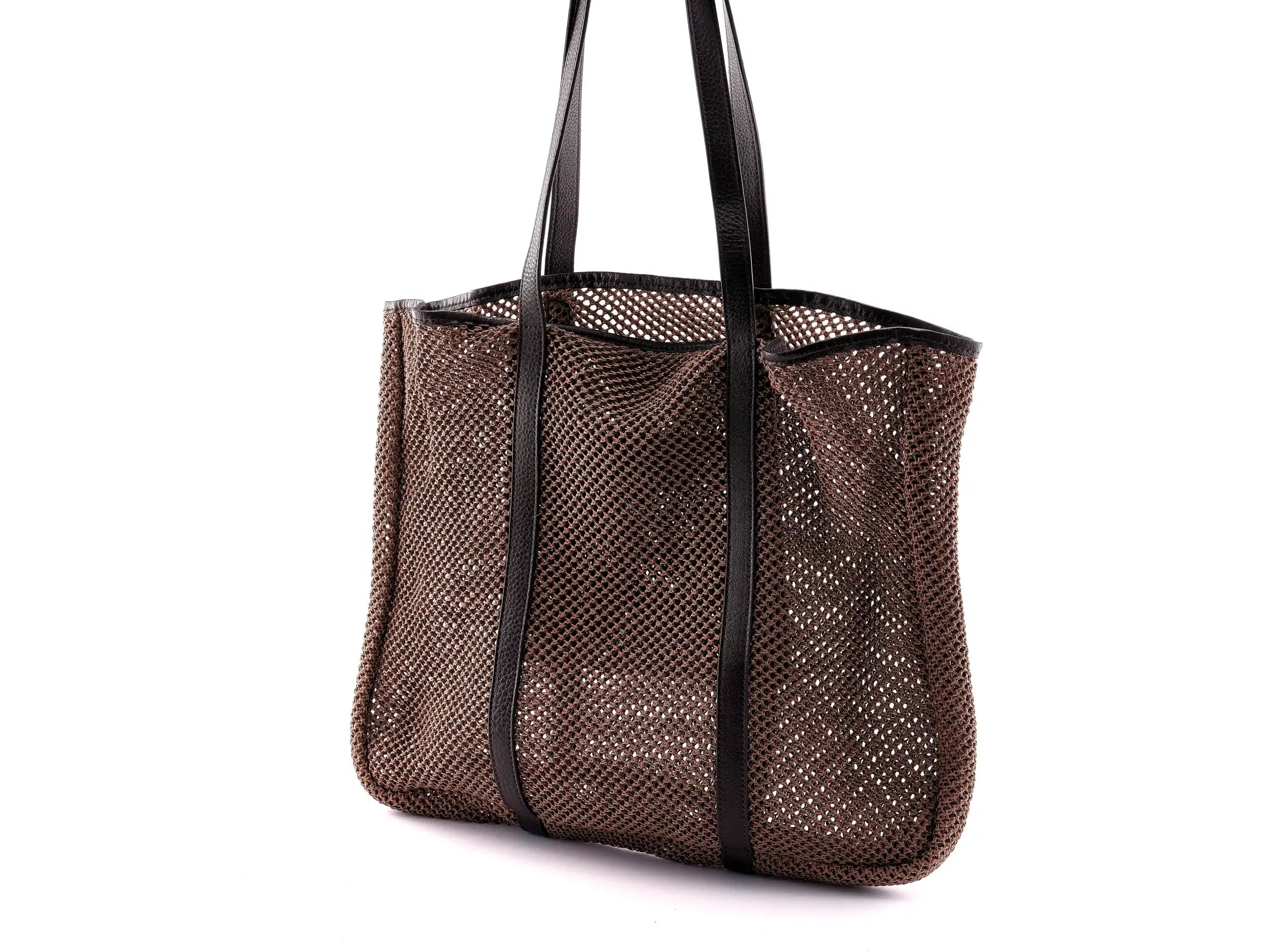 Brown woven beach bag with dark brown leather handles on a white background