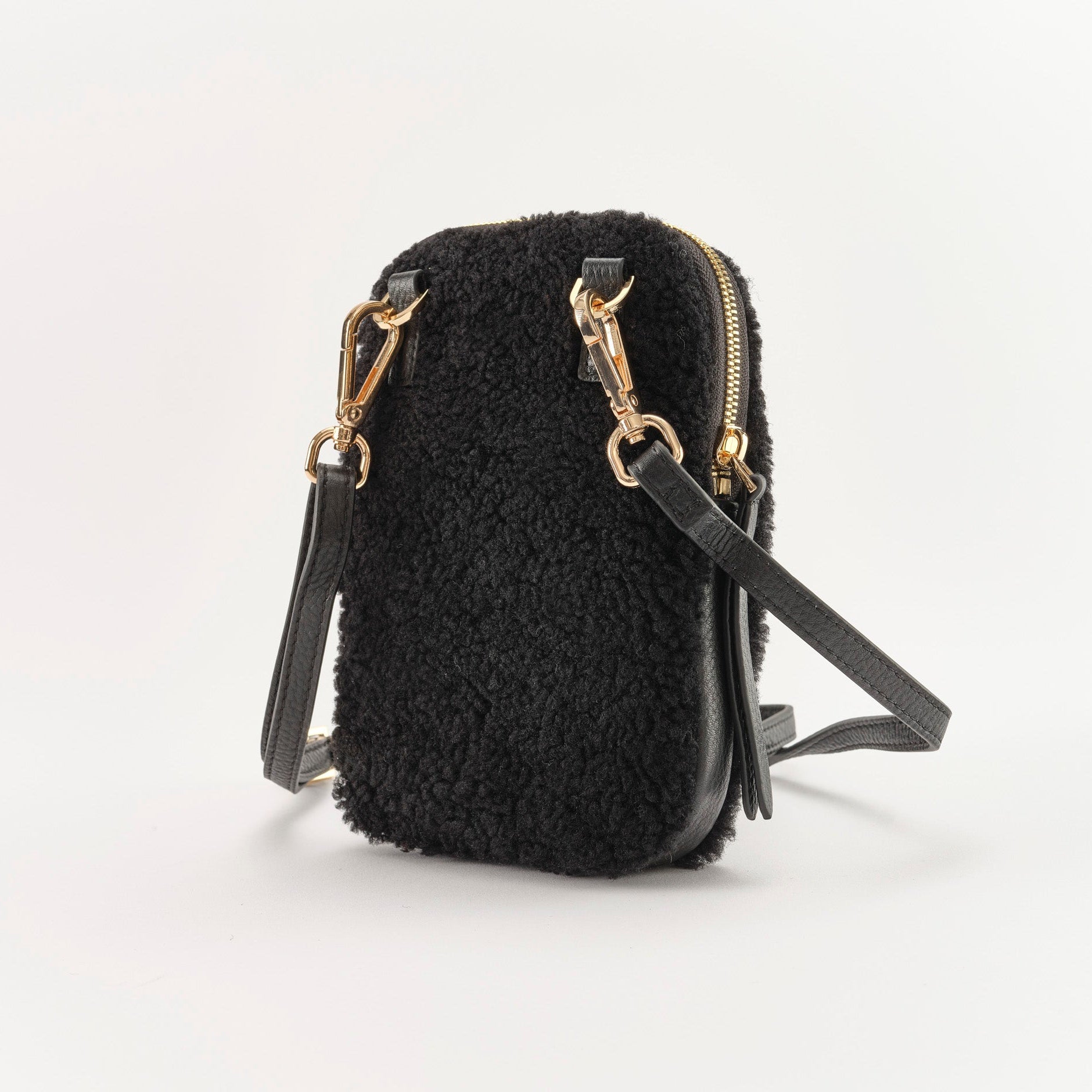 Black textured handbag with gold zippers on a white background