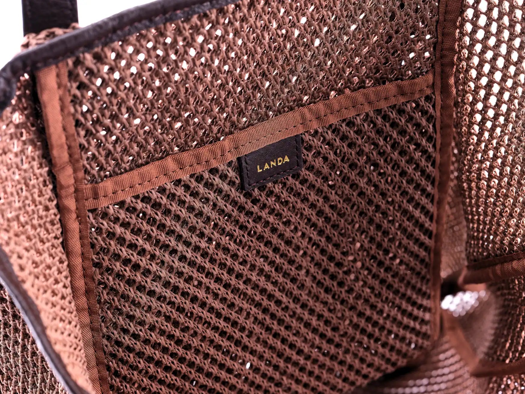Close-up of a internal pocket in brown woven beach bag with 'Landa' branding.